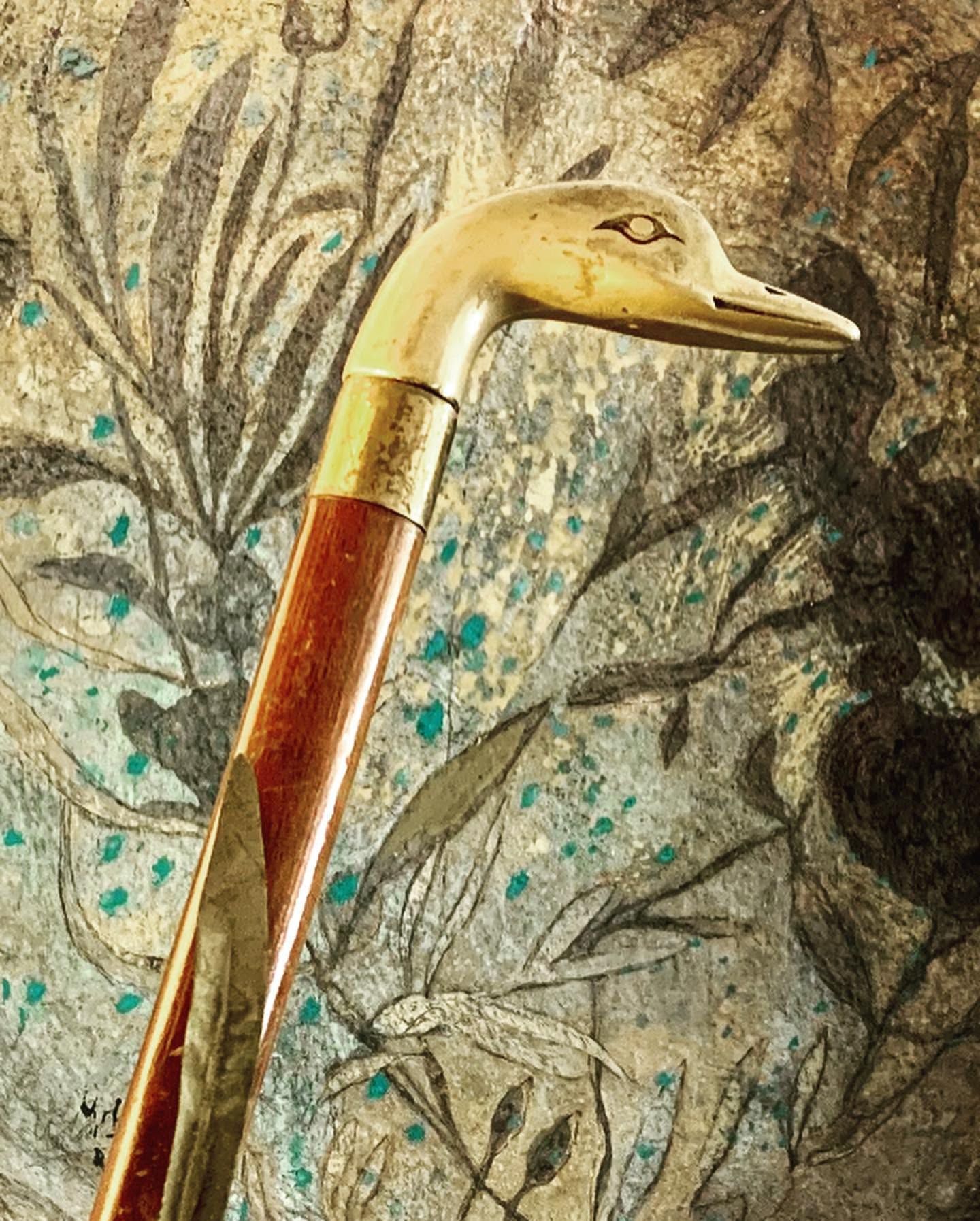 A brass bird-head handle against a botanical bowl